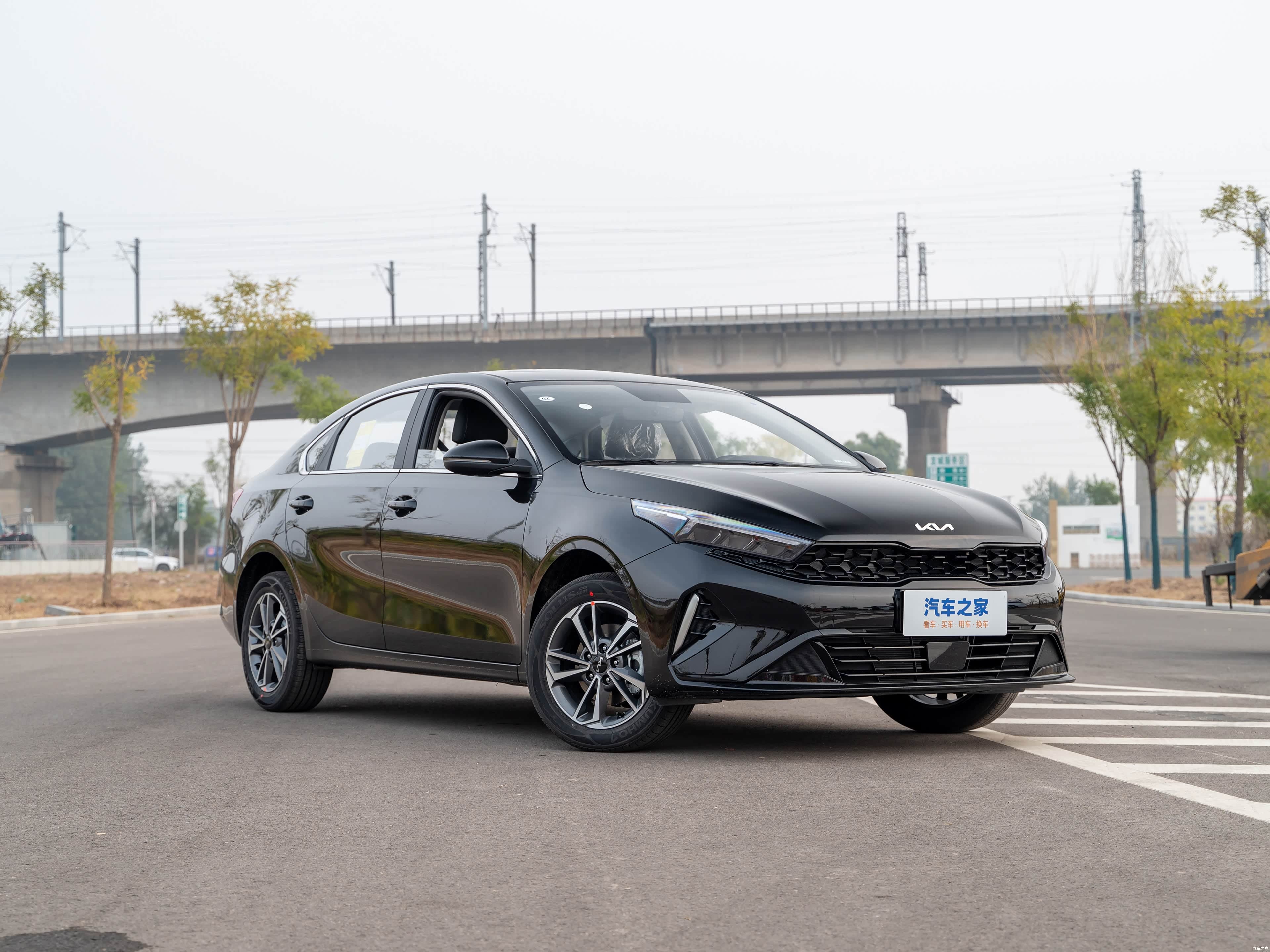 Чёрный седан Kia K3 на городской дороге