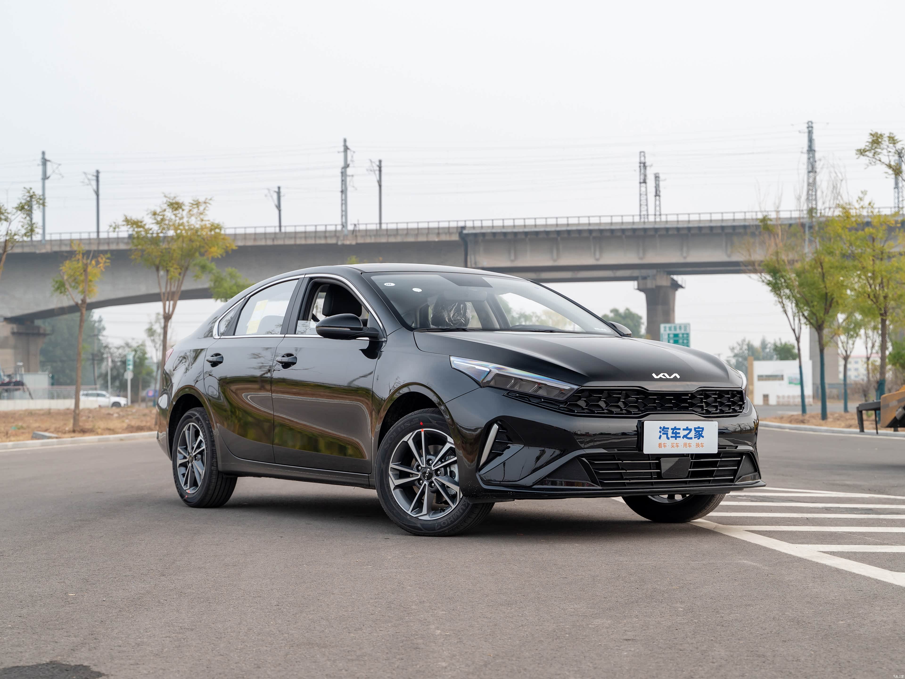 Чёрный седан Kia K3 на городской дороге